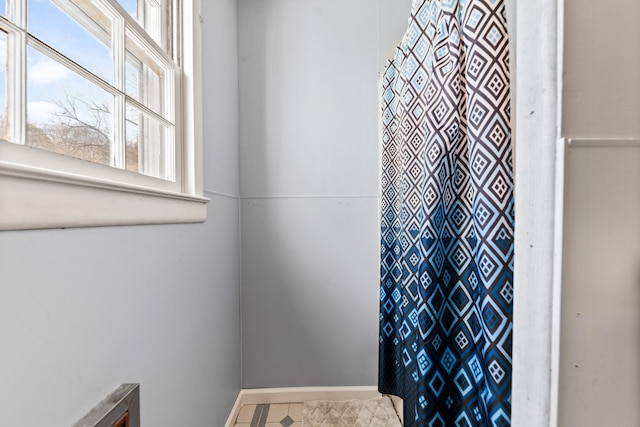 bathroom featuring curtained shower and baseboards