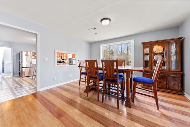 dining area featuring baseboards, visible vents, and light wood-style floors