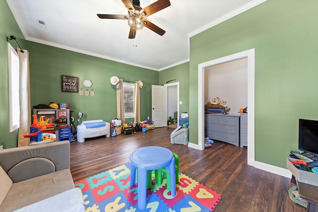 recreation room featuring a ceiling fan, crown molding, baseboards, and wood finished floors