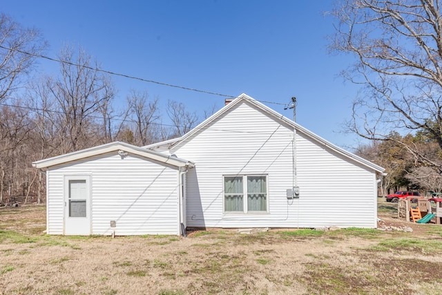 rear view of property featuring a yard and a playground