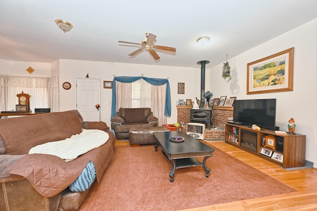 living room with hardwood / wood-style flooring, a wood stove, and ceiling fan