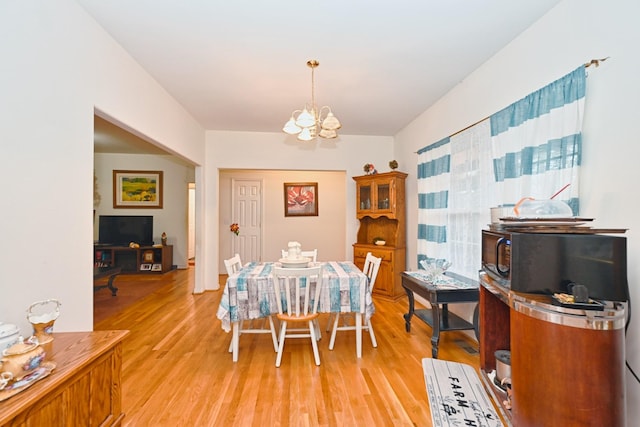 dining area featuring light wood-type flooring and a notable chandelier