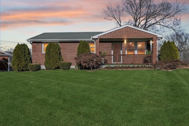 single story home featuring a porch and a lawn