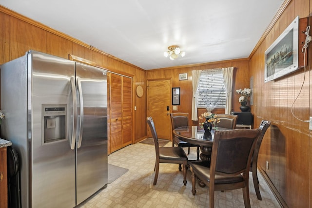 dining room with ornamental molding and wood walls