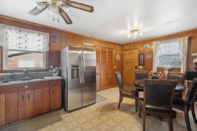 dining room featuring sink, crown molding, ceiling fan, and wood walls