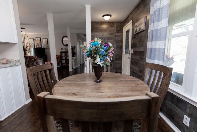 dining space featuring wooden walls and dark hardwood / wood-style flooring