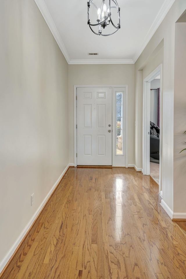 entrance foyer with ornamental molding, a chandelier, and light wood-type flooring