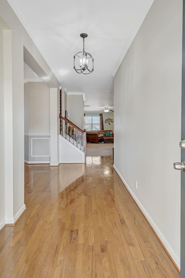 entrance foyer featuring crown molding, light hardwood / wood-style floors, and a chandelier