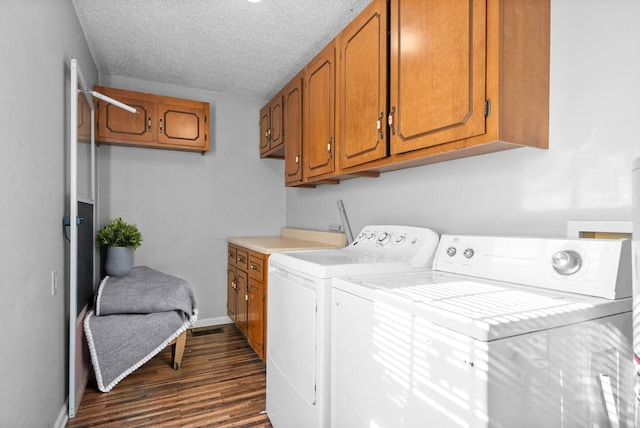 laundry area featuring cabinets, dark hardwood / wood-style floors, independent washer and dryer, and a textured ceiling