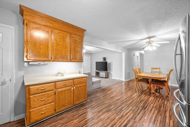 kitchen with stainless steel refrigerator, ceiling fan, dark hardwood / wood-style flooring, and a textured ceiling