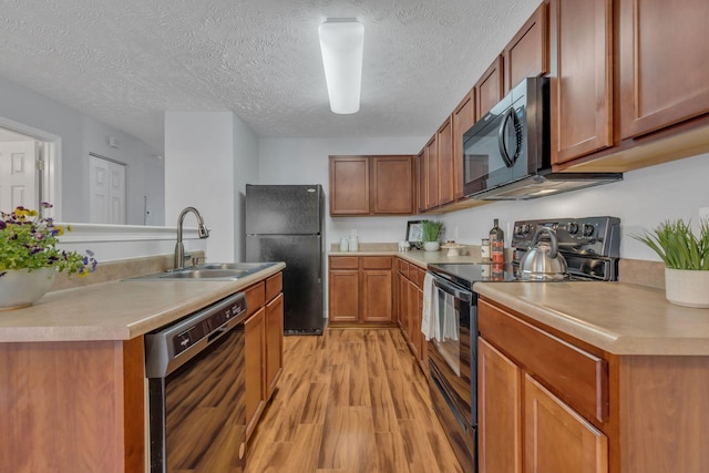 kitchen with sink, a textured ceiling, light wood-type flooring, and black appliances