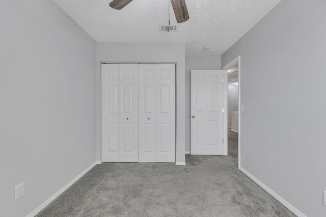 unfurnished bedroom featuring ceiling fan, a closet, light carpet, and a textured ceiling