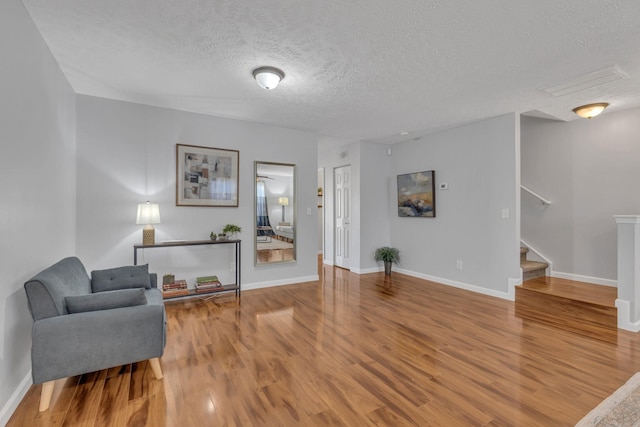 living area with hardwood / wood-style flooring and a textured ceiling