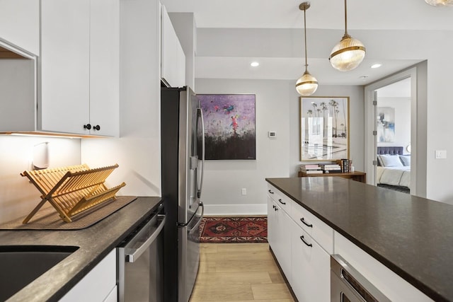 kitchen with pendant lighting, sink, white cabinetry, stainless steel appliances, and light hardwood / wood-style floors