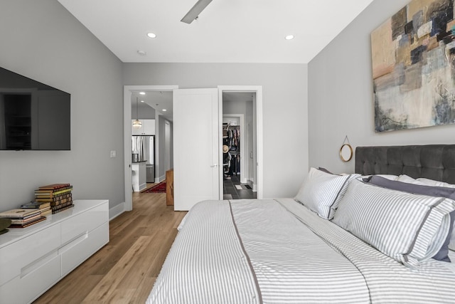 bedroom with ceiling fan, a spacious closet, and light hardwood / wood-style floors