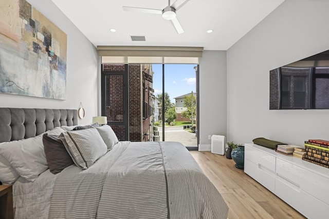 bedroom featuring a wall of windows, access to outside, ceiling fan, and light wood-type flooring