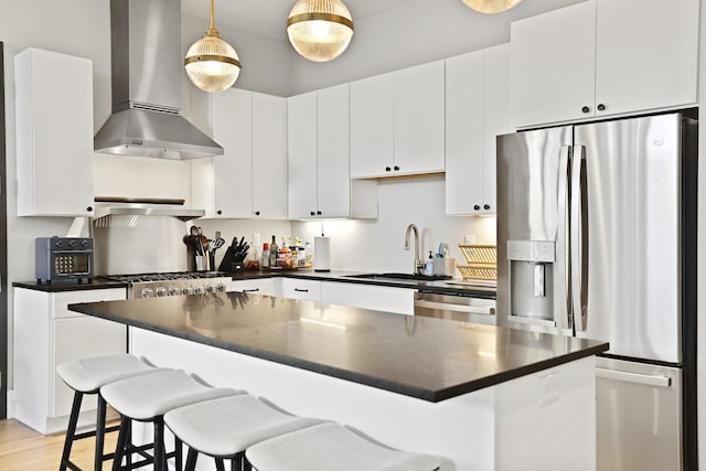 kitchen featuring pendant lighting, sink, appliances with stainless steel finishes, white cabinetry, and range hood