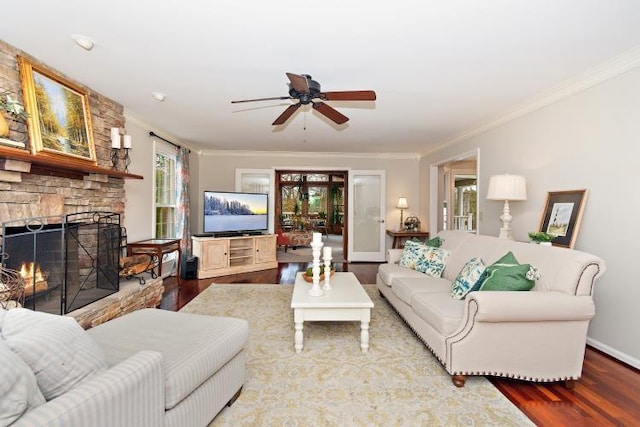 living room with crown molding, hardwood / wood-style floors, a stone fireplace, and ceiling fan