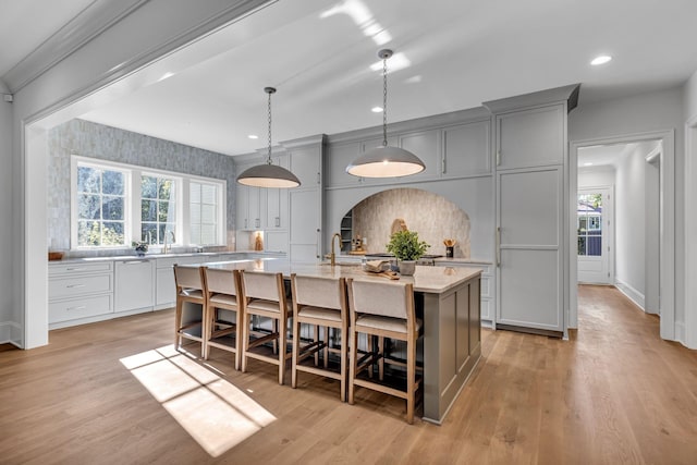 kitchen with gray cabinets, a kitchen island with sink, and a kitchen breakfast bar