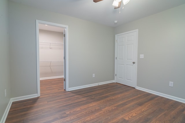 unfurnished bedroom with dark wood-type flooring, a walk in closet, ceiling fan, and a closet