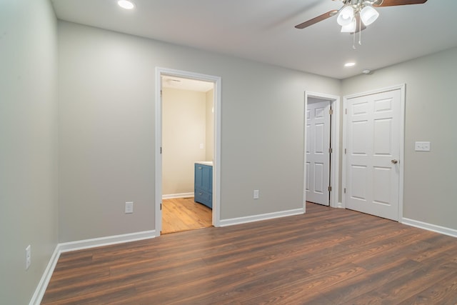 unfurnished bedroom featuring connected bathroom, dark hardwood / wood-style floors, and ceiling fan