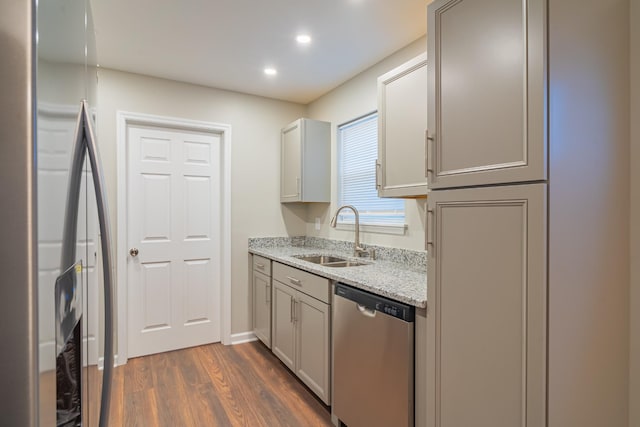 kitchen featuring sink, light stone counters, appliances with stainless steel finishes, dark hardwood / wood-style floors, and gray cabinets