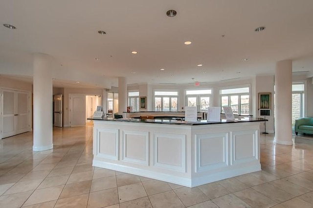 kitchen featuring white cabinetry, light tile patterned floors, decorative columns, and a spacious island