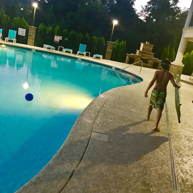 view of swimming pool with area for grilling, exterior fireplace, and a patio area