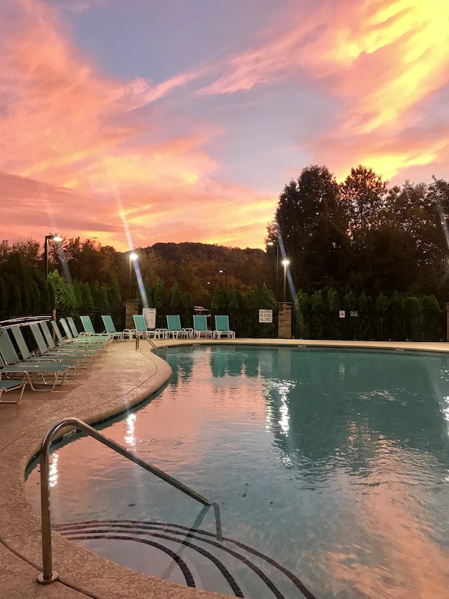 pool at dusk featuring a patio