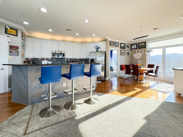 400 Warioto Way Unit 716, Ashland City, TN 37015 - kitchen with appliances with stainless steel finishes, ornamental molding, light wood-style floors, backsplash, and a kitchen bar