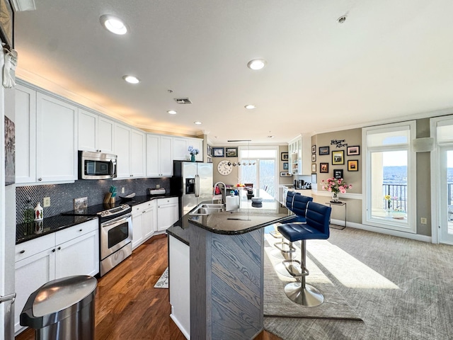 400 Warioto Way Unit 716, Ashland City, TN 37015 - kitchen with appliances with stainless steel finishes, a kitchen breakfast bar, white cabinetry, decorative backsplash, and a sink