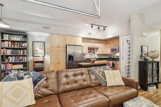 living room with a high ceiling, rail lighting, and light hardwood / wood-style floors