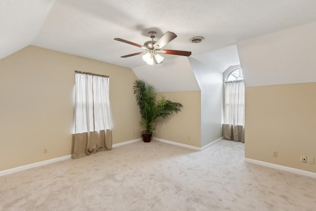 additional living space with vaulted ceiling, light carpet, and ceiling fan