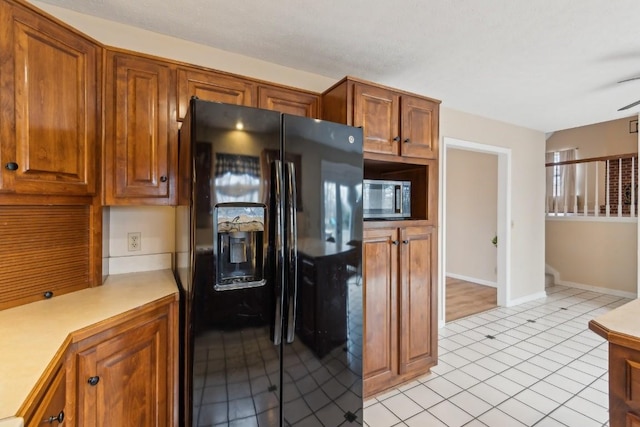 kitchen featuring light tile patterned floors and black refrigerator with ice dispenser