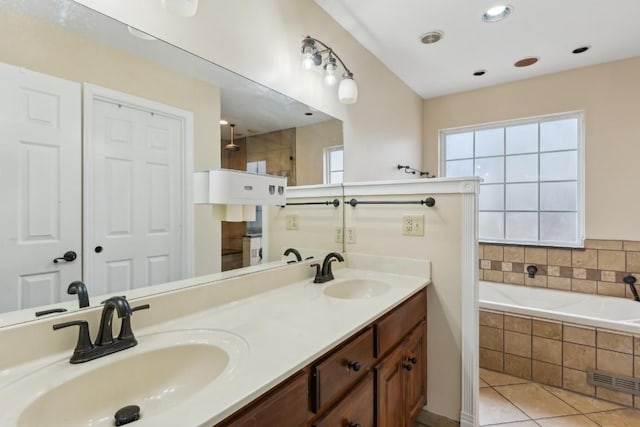 bathroom with tile patterned flooring, tiled tub, and vanity