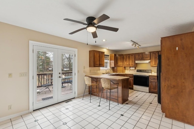 kitchen featuring light tile patterned flooring, white electric range, a kitchen bar, kitchen peninsula, and french doors