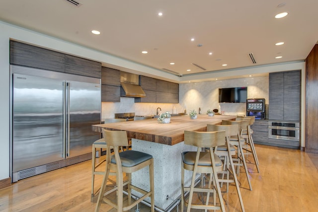 kitchen with stainless steel appliances, a breakfast bar, wooden counters, and light wood-type flooring