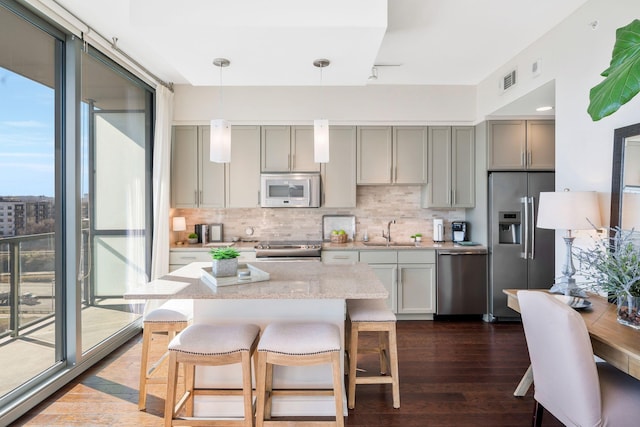 kitchen featuring gray cabinets, appliances with stainless steel finishes, decorative light fixtures, sink, and decorative backsplash