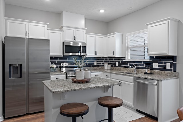 kitchen with sink, a kitchen island, white cabinets, and appliances with stainless steel finishes