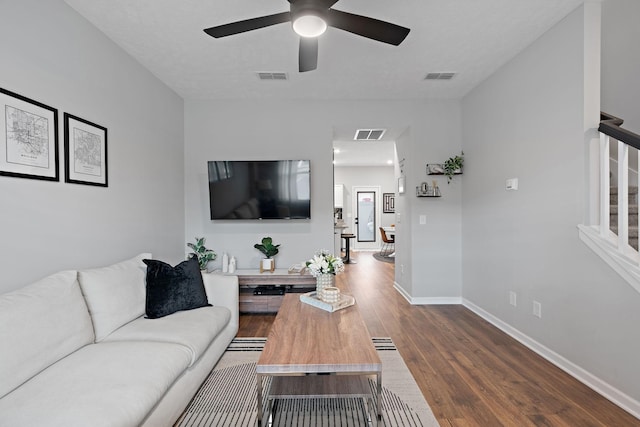 living room featuring dark wood-type flooring and ceiling fan