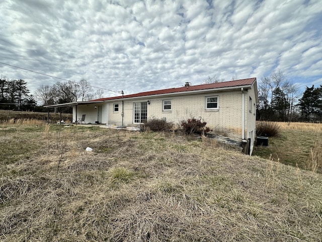 rear view of house featuring metal roof and brick siding