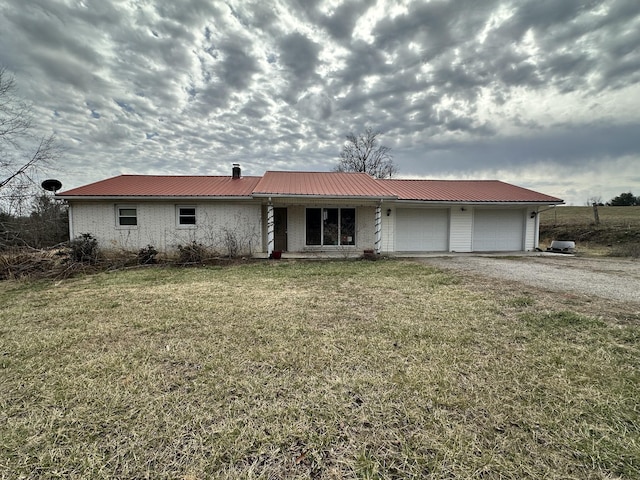 ranch-style house featuring brick siding, an attached garage, a front yard, metal roof, and driveway