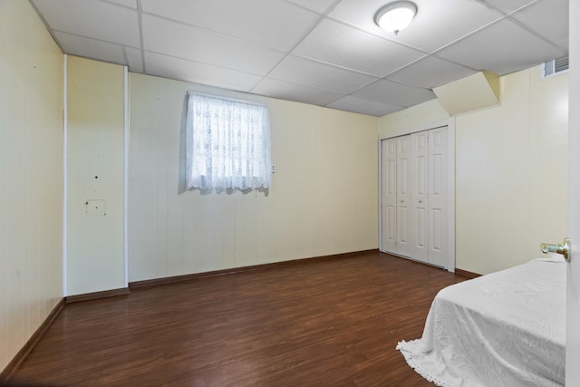 bedroom with dark hardwood / wood-style flooring, a closet, and a drop ceiling