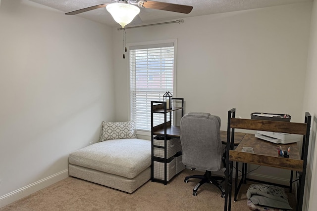 carpeted home office featuring a textured ceiling and ceiling fan