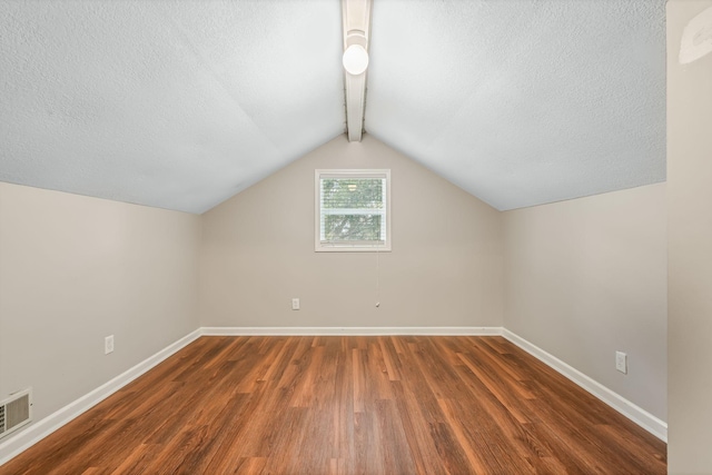 bonus room featuring dark hardwood / wood-style flooring, a textured ceiling, and vaulted ceiling with beams