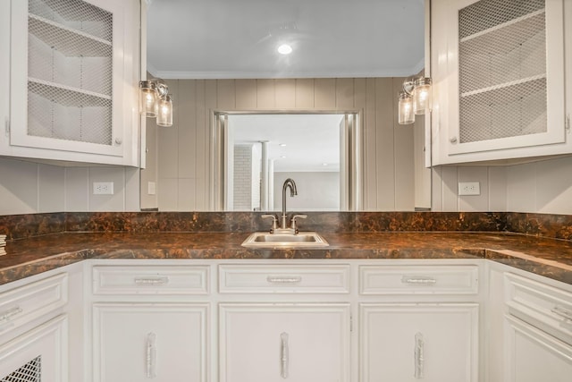 kitchen with ornamental molding, decorative light fixtures, sink, and white cabinets