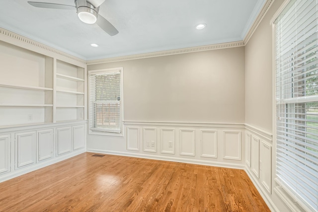 empty room featuring crown molding, ceiling fan, light hardwood / wood-style floors, and built in shelves