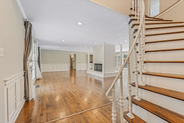 stairway with hardwood / wood-style floors and a fireplace