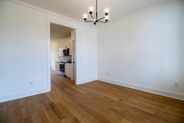 unfurnished dining area featuring an inviting chandelier, ornamental molding, wood finished floors, and baseboards
