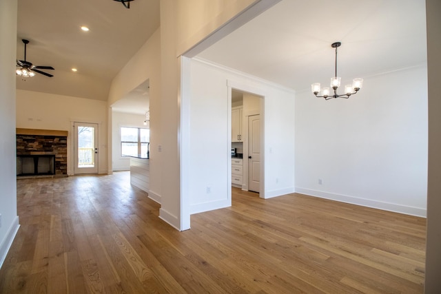 interior space featuring ceiling fan with notable chandelier, wood finished floors, baseboards, and crown molding